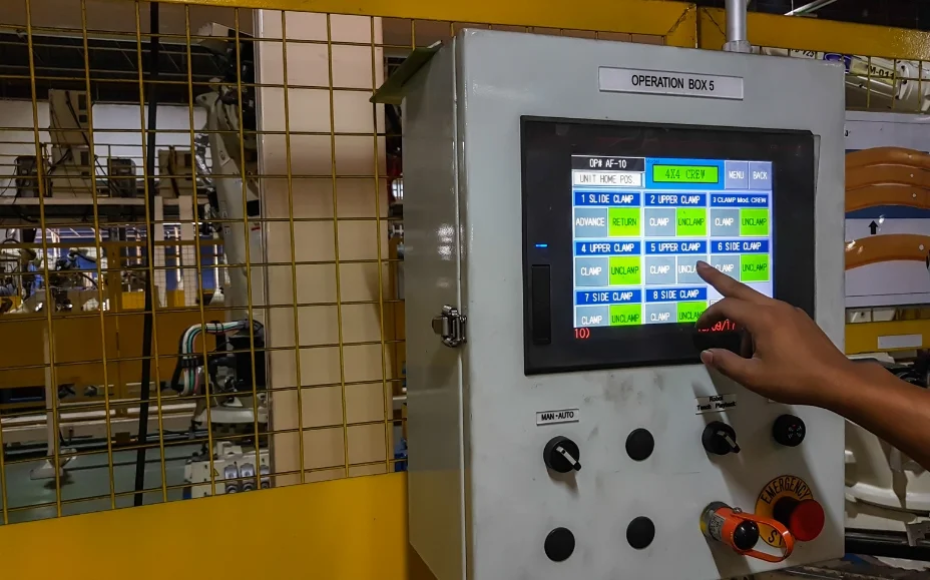 Touchscreen industrial control panel labeled 'Operation Box 5' being operated by a person in an industrial setting, with a finger selecting on-screen options
