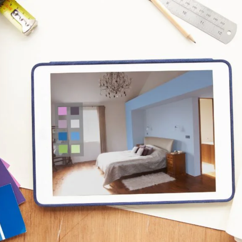 Tablet displaying a modern bedroom with blue accent wall, chandelier, bed, and wooden nightstand on a white rug.