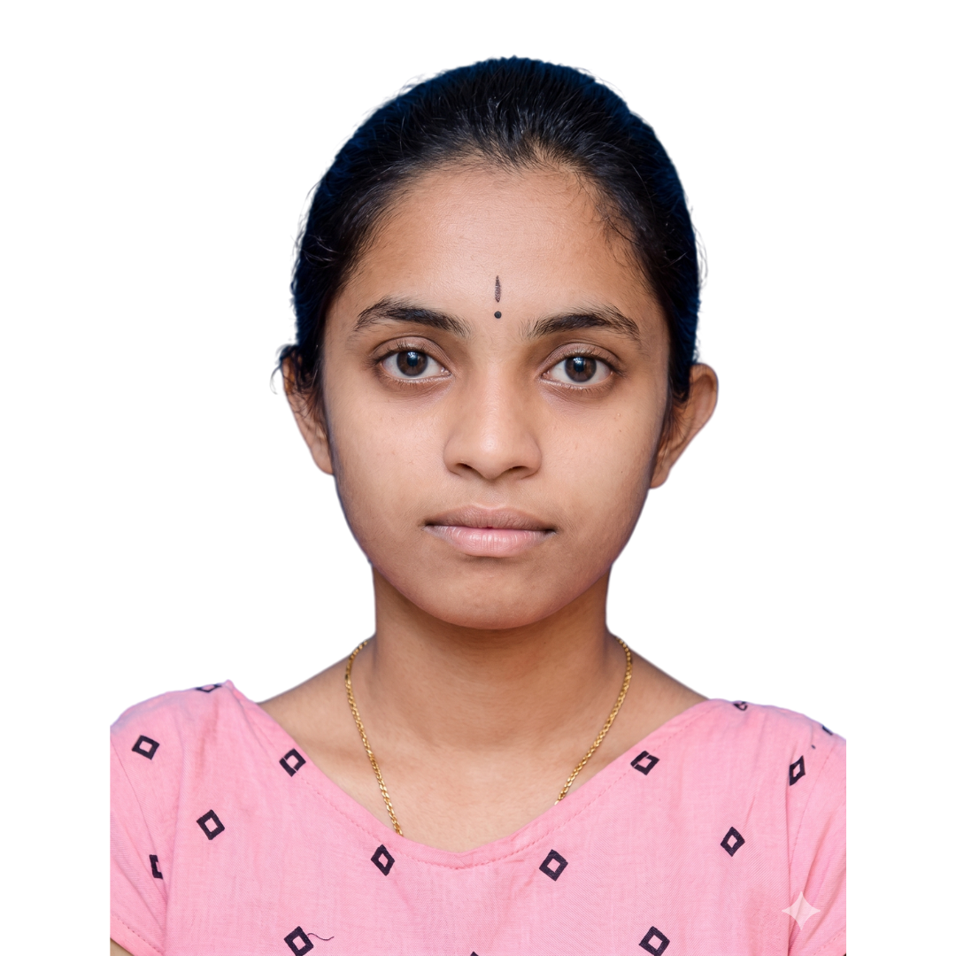 Front-facing portrait of a young woman with a small bindi, wearing a pink patterned top and a gold necklace against a white background.